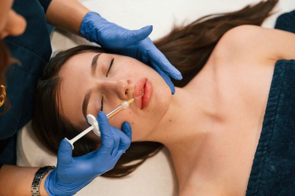 Cosmetologist does injection for lips augmentation. Women's cosmetology in the beauty salon.